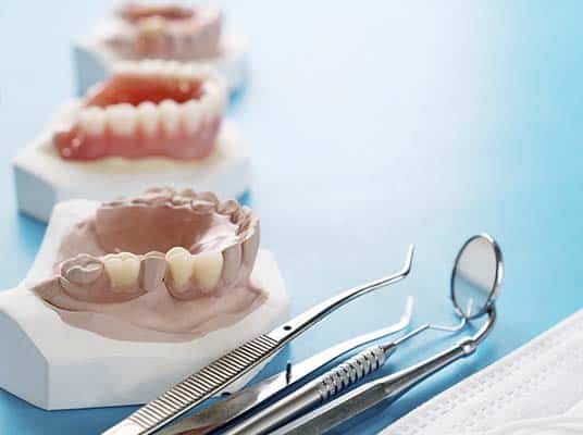 closeup of womans hand holding a teeth denture